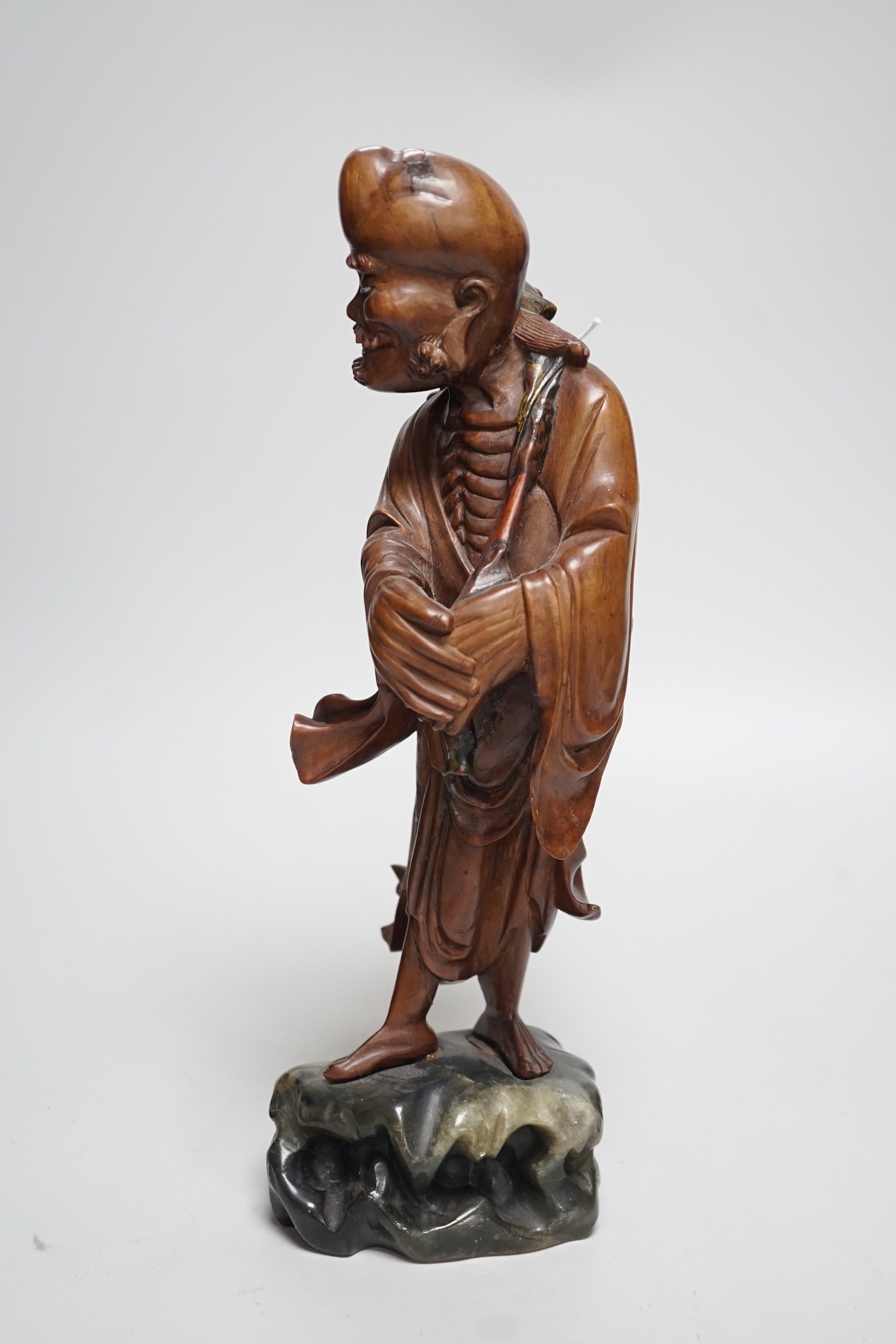 An early 20th century Chinese hardwood carving of a luohan, on soapstone base, 36cm tall